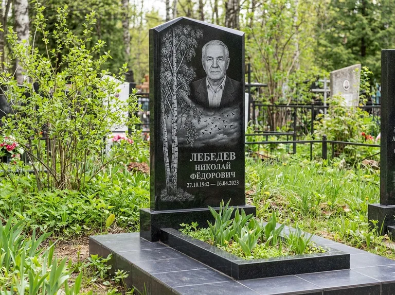 Памятник с гравировкой берёзы: вертикальная стела со скошенным верхом — берёза и стая птиц в небе, гранитный цоколь с тёмной плиткой, работа «Лебедев» в Южно-Сахалинске