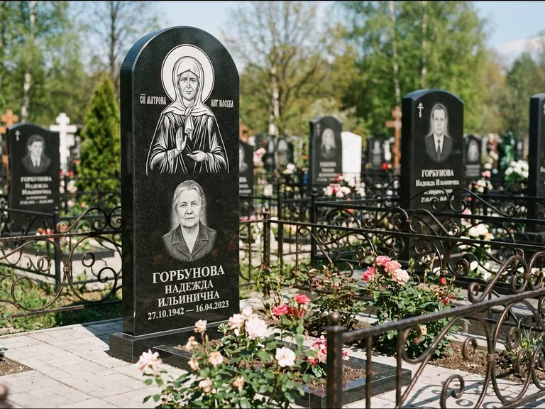 Памятник с гравировкой иконы: стела с арочным верхом и киотом под образ — гравировка образа Матроны Московской, гранитный цоколь с тёмной плиткой, работа «Ковалёв» в Южно-Сахалинске