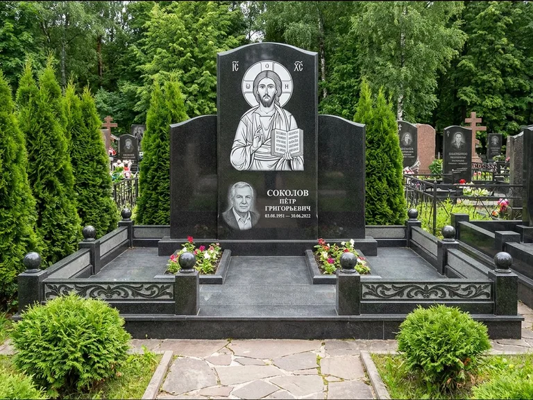 Памятник с гравировкой иконы: широкая горизонтальная лежачая плита-стела — икона в резной рамке-киоте, серая гравийная отсыпка с бордюром, работа «Богданова» в Южно-Сахалинске