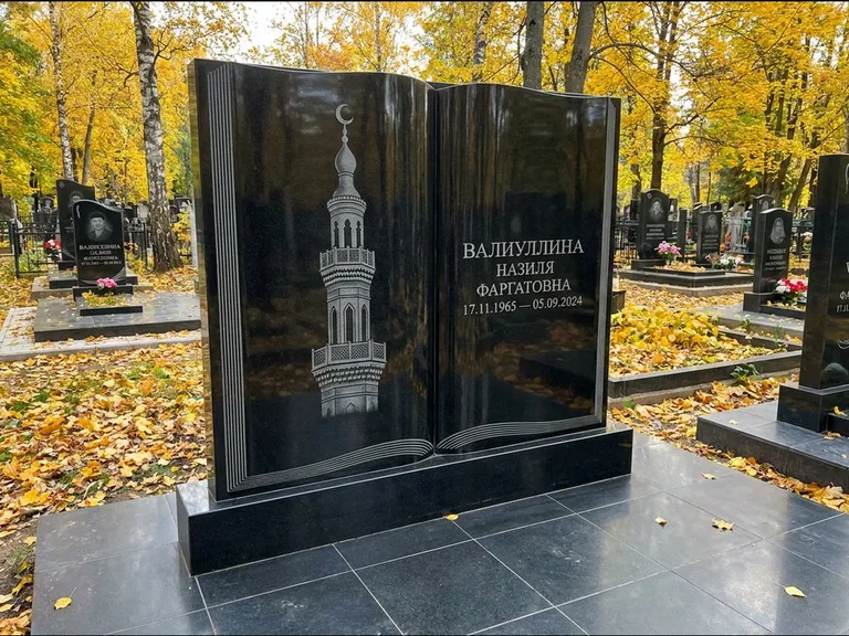 Мусульманский памятник с гравировкой мечети: стела в форме раскрытой книги на подставке — белая гравировка силуэта мечети с минаретами, цоколь тёмной плиткой, работа «Исмаилова» в Южно-Сахалинске