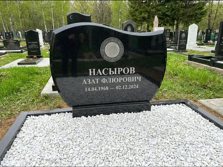 Мусульманский памятник: стела с волнообразным скошенным верхом — гравировка мечети под полумесяцем и звёздами, белая мраморная крошка с бордюром, работа «Насыров» в Южно-Сахалинске