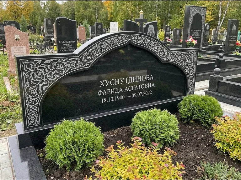Мусульманский памятник: вытянутая горизонтальная семейная стела с аркой — белая гравировка силуэта мечети с минаретами, участок с декоративными кустами, работа «Зарипова» в Южно-Сахалинске