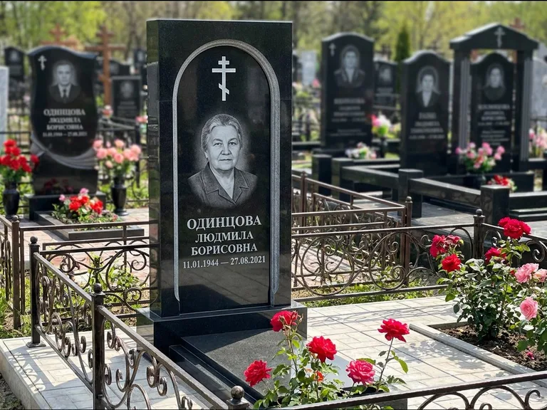 Памятник из чёрного гранита — скромная невысокая стела с крестом с терновым венцом, работа «Лаврентьева» в Южно-Сахалинске