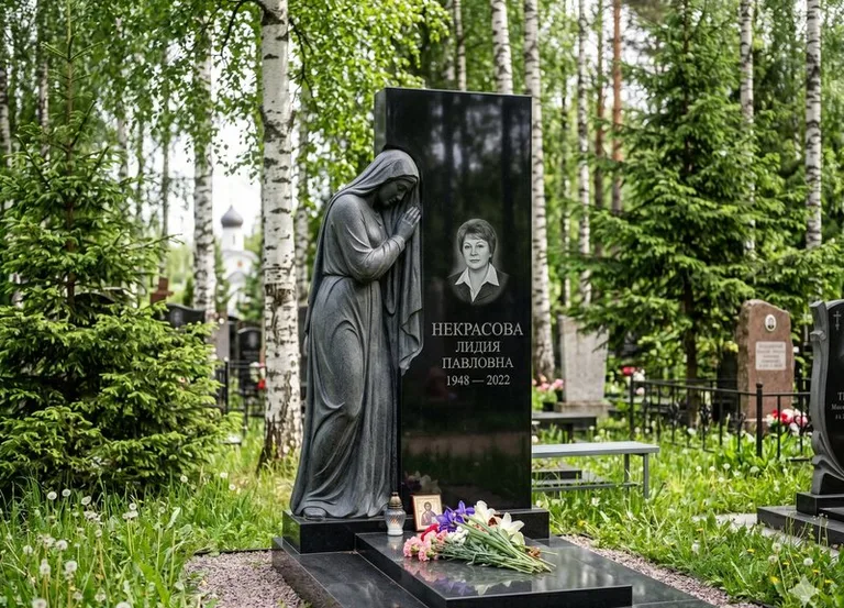 Гранитная фигура скорбящего мужчины у чёрной стелы в Южно-Сахалинске